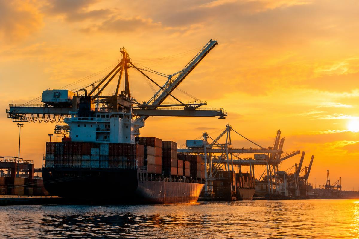 Containerskip og havnekraner i solnedgang